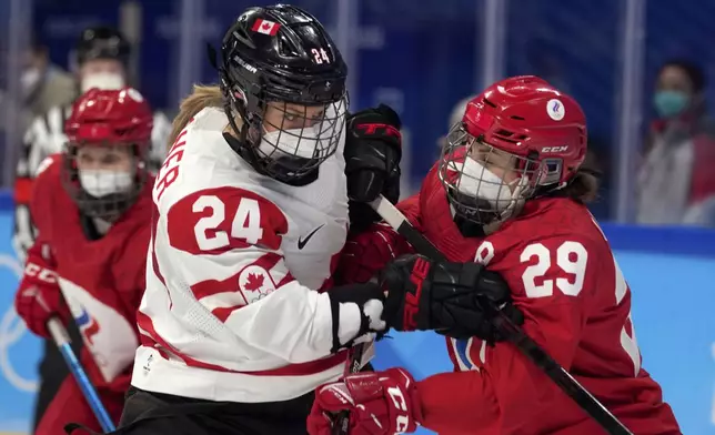 FILE - Canada's Natalie Spooner (24) and Russian Olympic Committee's Alexandra Vafina (29) wear COVID masks during a preliminary round women's hockey game at the 2022 Winter Olympics, Feb. 7, 2022, in Beijing. (AP Photo/Petr David Josek, File)