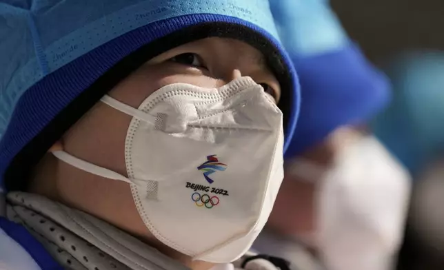 FILE - A member of the medical staff wears a protective mask as she watches a women's normal hill ski jumping training session at the 2022 Winter Olympics, Feb. 4, 2022, in Zhangjiakou, China. (AP Photo/Matthias Schrader, file)