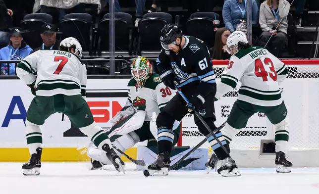 Utah Mammoth left wing Lawson Crouse (67), Minnesota Wild defender Brock Faber (7), Wild defender Quinn Hughes (43) and Wild goaltender Jesper Wallstedt (30) battle for the puck in front of the net during the second period of an NHL hockey game, Friday, Feb. 27, 2026, in Salt Lake City. (AP Photo/Tyler Tate)