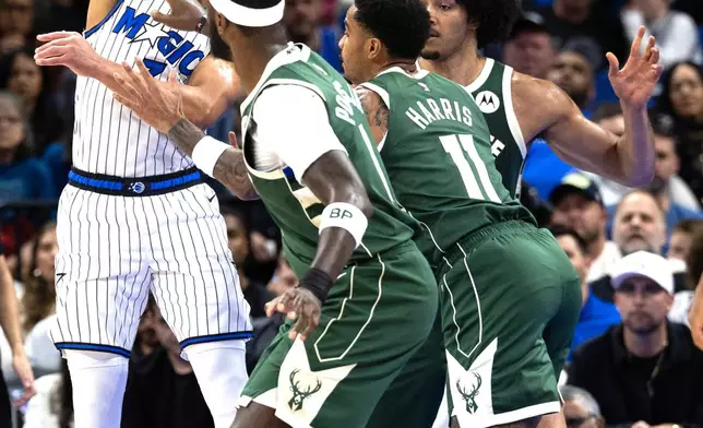 Orlando Magic guard Desmond Bane, left, passes the ball over Milwaukee Bucks defenders during the first half of an NBA basketball game, Wednesday, Feb. 11, 2026, in Orlando, Fla. (AP Photo/Willie J. Allen Jr.)
