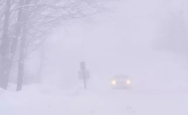 A pick-up truck drives in nearly white-out conditions during a winter storm, Monday, Feb. 23, 2026, in Derry, N.H. (AP Photo/Charles Krupa)