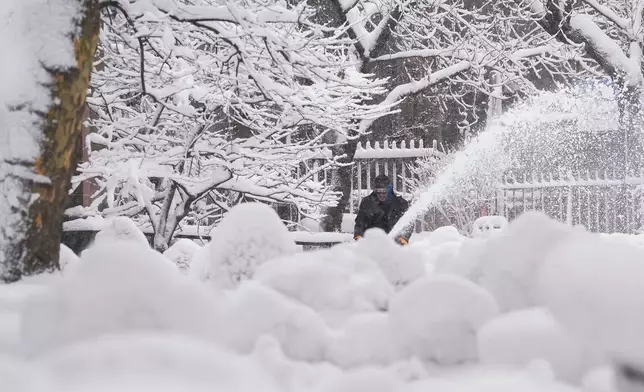 A groundskeeper clears snow from the walkways inside the Trinity Church graveyard in lower Manhattan during a snow storm, Monday, Feb. 23, 2026, in New York. (AP Photo/Seth Wenig)
