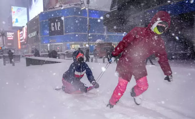 Hannah and Astrid Grimskog play in Times Square during a snow storm, Monday, Feb. 23, 2026, in New York. (AP Photo/Seth Wenig)