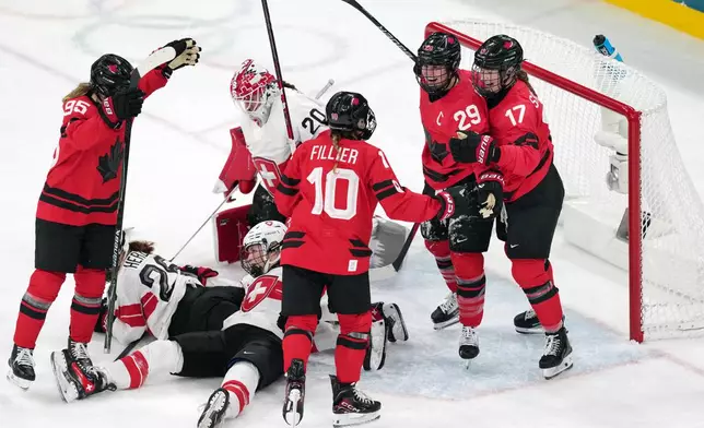 Canada's Marie-Philip Poulin (29) celebrates with Ella Shelton (17) and Sarah Fillier (10) after Poulin scored her second goal of the game against Switzerland during the second period of a women's ice hockey semifinal match at the 2026 Winter Olympics, in Milan, Italy, Monday, Feb. 16, 2026. (AP Photo/Carolyn Kaster)