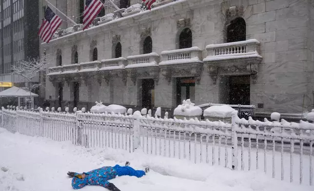 Pierce Harvey, 13, plays in the snow outside the New York Stock Exchange during a snow storm, Monday, Feb. 23, 2026, in New York. (AP Photo/Seth Wenig)