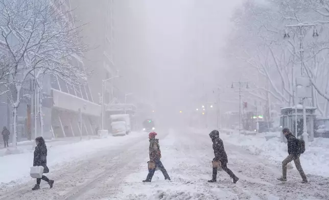 Pedestrians cross 42nd Street near Bryant Park during a snow storm, Monday, Feb. 23, 2026, in New York. (AP Photo/Seth Wenig)