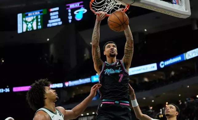 Miami Heat's Kel'el Ware (7) dunks over Milwaukee Bucks' Jericho Sims and Ryan Rollins during the second half of an NBA basketball game Tuesday, Feb. 24, 2026, in Milwaukee. (AP Photo/Aaron Gash)