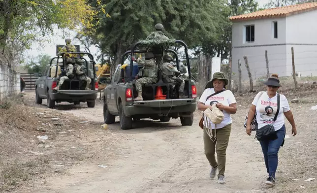 Members of a group that searches for missing people walk alongside soldiers in El Verde, Sinaloa state, Mexico, Monday, Feb. 8, 2026. (AP Photo/Juvencio Villanueva)