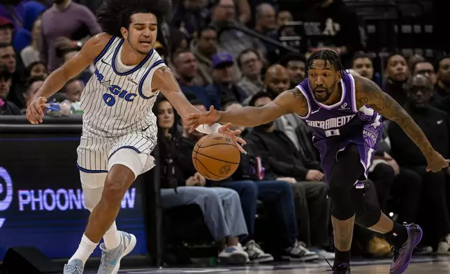 Orlando Magic guard Anthony Black, left, and Sacramento Kings guard Malik Monk, right, chase the ball during the first half of an NBA basketball game in Sacramento, Calif., Thursday, Feb. 19, 2026. (AP Photo/Randall Benton)