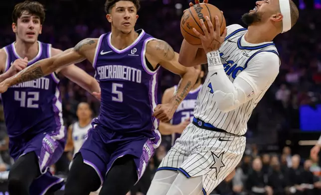 Orlando Magic guard Jalen Suggs, right, is guarded by Sacramento Kings center Maxime Raynaud (42) and guard Nique Clifford (5) during the first half of an NBA basketball game in Sacramento, Calif., Thursday, Feb. 19, 2026. (AP Photo/Randall Benton)