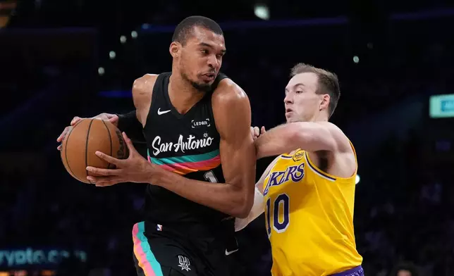 San Antonio Spurs forward Victor Wembanyama (1) is defended by Los Angeles Lakers guard Luke Kennard (10) during the first half of an NBA basketball game Tuesday, Feb. 10, 2026, in Los Angeles. (AP Photo/Jae C. Hong)