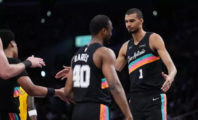 San Antonio Spurs forward Victor Wembanyama (1) greets teammates during the first half of an NBA basketball game against the Los Angeles Lakers Tuesday, Feb. 10, 2026, in Los Angeles. (AP Photo/Jae C. Hong)