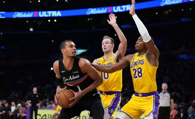 San Antonio Spurs forward Victor Wembanyama (1) is double-teamed by Los Angeles Lakers forward Rui Hachimura (28) and guard Luke Kennard (10) during the first half of an NBA basketball game Tuesday, Feb. 10, 2026, in Los Angeles. (AP Photo/Jae C. Hong)