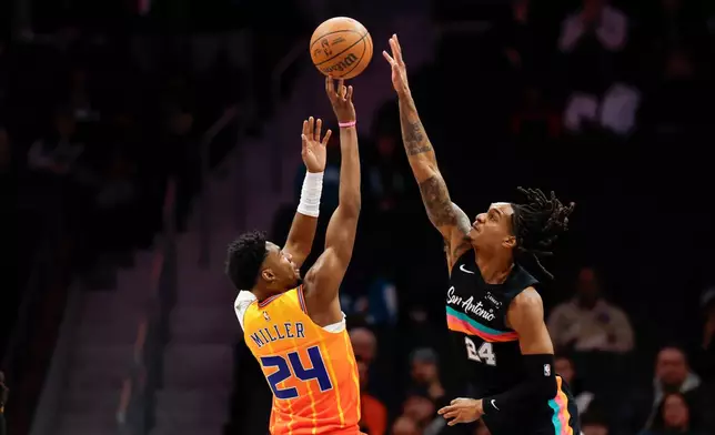 Charlotte Hornets forward Brandon Miller, left, shoots against San Antonio Spurs guard Devin Vassell during the first half of an NBA basketball game in Charlotte, N.C., Saturday, Jan. 31, 2026. (AP Photo/Nell Redmond)