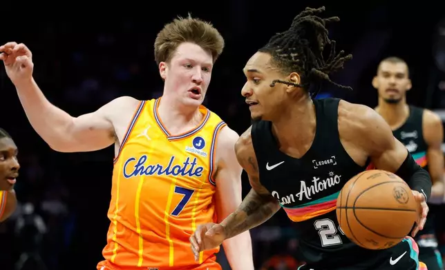 San Antonio Spurs guard Devin Vassell, right, drives to the basket against Charlotte Hornets guard Kon Knueppel (7) during the first half of an NBA basketball game in Charlotte, N.C., Saturday, Jan. 31, 2026. (AP Photo/Nell Redmond)