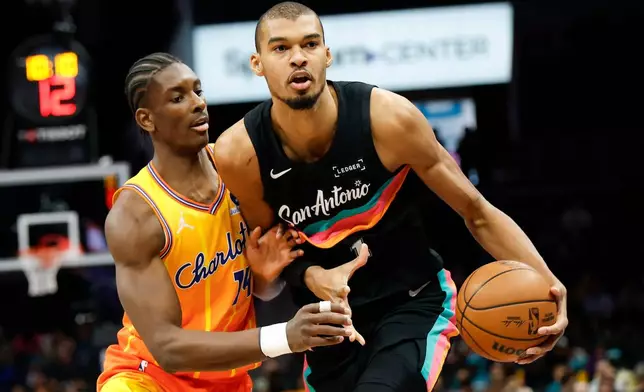 San Antonio Spurs forward Victor Wembanyama, right, moves the ball against Charlotte Hornets forward Moussa Diabate during the first half of an NBA basketball game in Charlotte, N.C., Saturday, Jan. 31, 2026. (AP Photo/Nell Redmond)