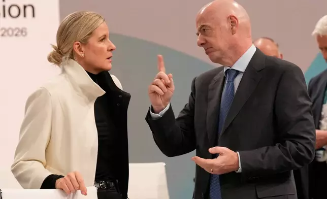 IOC President Kirsty Coventry, left, speaks to FIFA President and IOC member Gianni Infantino, during the opening of the IOC Session, ahead of the 2026 Winter Olympics, in Milan, Italy, Tuesday, Feb. 3, 2026. (AP Photo/Luca Bruno)