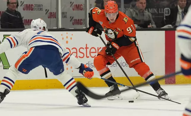 Anaheim Ducks center Leo Carlsson (91) looks to pass as Edmonton Oilers defenseman Darnell Nurse defends during the first period of an NHL hockey game Wednesday, Feb. 25, 2026, in Anaheim, Calif. (AP Photo/Gregory Bull)