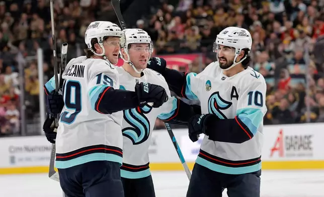 Seattle Kraken left wing Jared McCann (19) celebrates with defenseman Vince Dunn, center, and center Matty Beniers (10) after scoring against the Vegas Golden Knights during the first period of an NHL hockey game Saturday Jan. 31, 2026, in Las Vegas. (AP Photo/Steve Marcus)