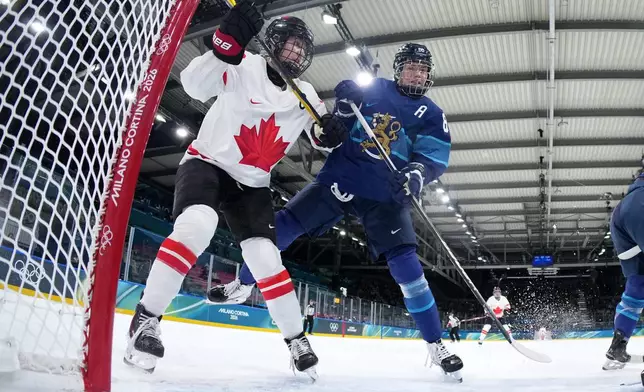 Canada's Brianne Jenner, left, challenges with Finland's Ronja Savolainen, during a preliminary round match of women's ice hockey between Finland and Canada at the 2026 Winter Olympics, in Milan, Italy, Thursday, Feb. 12, 2026. (Sun Fei/Pool Photo via AP)
