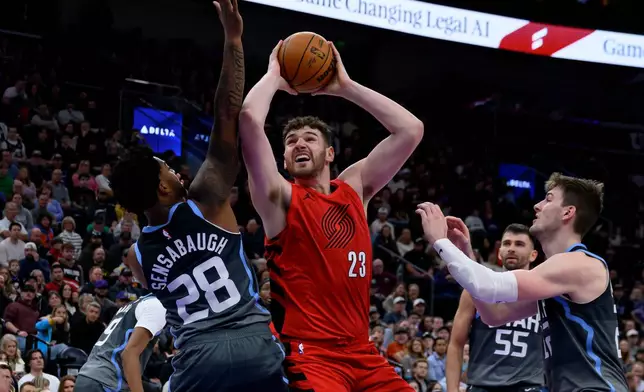 Portland Trail Blazers center Donovan Clingan, center, goes to the basket guarded by Utah Jazz forward Brice Sensabaugh, left, and Utah Jazz forward Kyle Filipowski, right, during the first half of an NBA basketball game, Thursday, Feb. 12, 2026, in Salt Lake City. (AP Photo/Tyler Tate)