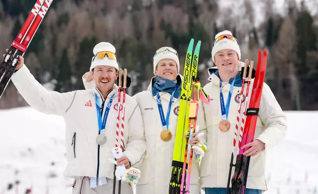 Gold medalist Johannes Hoesflot Klaebo, center, of Norway, poses flanked by silver medalist Ben Ogden, of the United States, left, and bronze medalist Oskar Opstad Vike, of Norway, on the podium of the cross-country skiing men's sprint classic at the 2026 Winter Olympics, in Tesero, Italy, Tuesday, Feb. 10, 2026. (AP Photo/Evgeniy Maloletka)