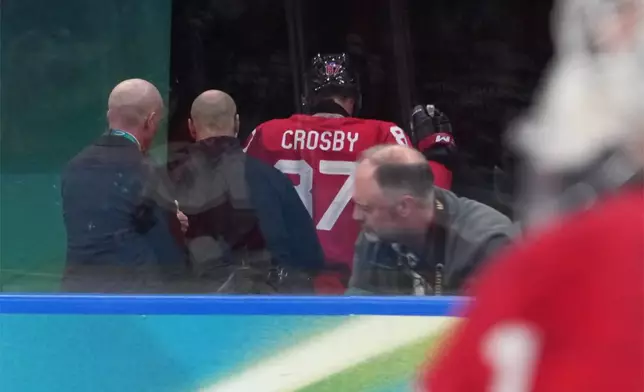 Canada's Sidney Crosby (87) is helped as he leaves the bench after being checked against the boards during the second period of a men's ice hockey quarterfinal game between Canada and Czechia at the 2026 Winter Olympics, in Milan, Italy, Wednesday, Feb. 18, 2026. (AP Photo/Carolyn Kaster)