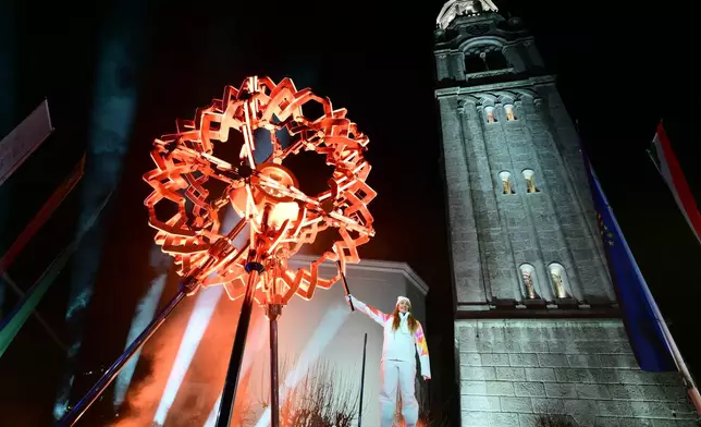 Final torchbearer Italian skier Sofia Goggia uses the torch of the Olympic flame to light the Olympic cauldron designed by Marco Balich during the Olympic opening ceremony at the 2026 Winter Olympics, in in Cortina d'Ampezzo, Italy, Friday, Feb. 6, 2026. (Stefano Rellandini/Pool Photo via AP)