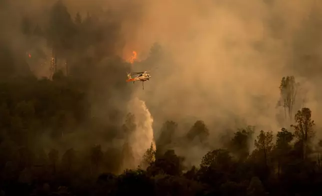 FILE - A helicopter drops water on the Pickett Fire as it burns into the Aetna Springs area of Napa County, Calif., Aug. 23, 2025. (AP Photo/Noah Berger, File)