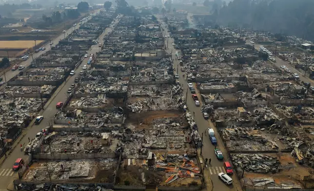 FILE - Cars line the streets near wildfire-burned homes in Tome, Chile, Jan. 19, 2026. (AP Photo/Javier Torres, FIle)