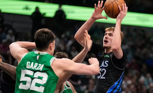 Dallas Mavericks' Cooper Flagg (32) takes a shot as Boston Celtics' Luka Garza (52) and Hugo Gonzalez, rear, defend in the first half of an NBA basketball game Tuesday, Feb. 3, 2026, in Dallas. (AP Photo/Tony Gutierrez)