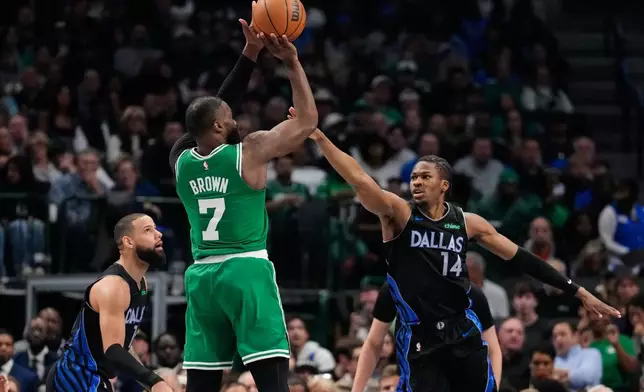 Boston Celtics guard Jaylen Brown (7) shoots as Dallas Mavericks' Caleb Martin, left, and Miles Kelly (14) defend in the first half of an NBA basketball game Tuesday, Feb. 3, 2026, in Dallas. (AP Photo/Tony Gutierrez)