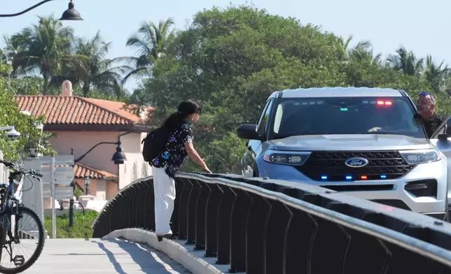 A Palm Beach County sheriff deputy talks to a bicyclist on the bridge leading to Mar-a-Lago Sunday, Feb. 22, 2026, in Palm Beach, Fla. The U.S. Secret Service announced Sunday that an armed man was shot and killed after entering the secure perimeter of Mar-a-Lago, President Donald Trump's resort. (AP Photo/Marta Lavandier)