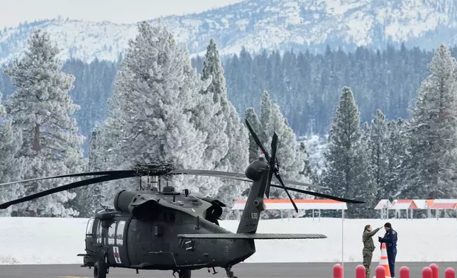 A member of the U.S. Army and a member of the California Highway Patrol speak on the runway at the Truckee Tahoe Airport as recovery efforts for a group of missing skiers continue in Truckee, Calif., Saturday, Feb. 21, 2026. (AP Photo/Godofredo A. Vásquez)