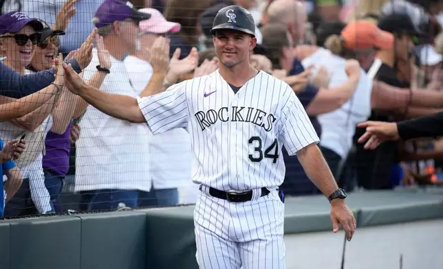 FILE - Colorado Rockies third base coach/infield coach Warren Schaeffer (34) greets fans during the team's ceremonial walk about the stadium after a baseball game, Oct. 1, 2023, in Denver. (AP Photo/David Zalubowski, File)