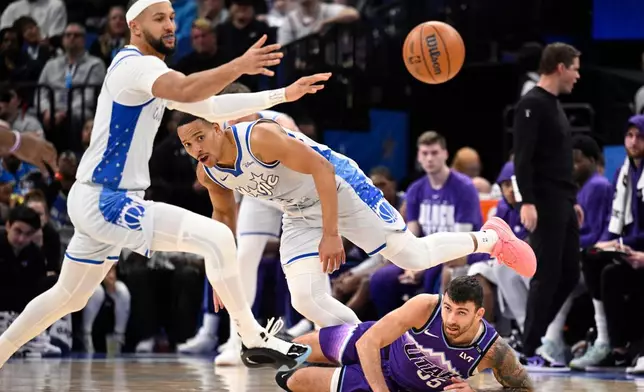 Orlando Magic guard Jalen Suggs, left, guard Desmond Bane (3) and Utah Jazz forward John Konchar (55) battle for a loose ball during the first half of an NBA basketball game, Saturday, Feb. 7, 2026, in Orlando, Fla. (AP Photo/Phelan M. Ebenhack)