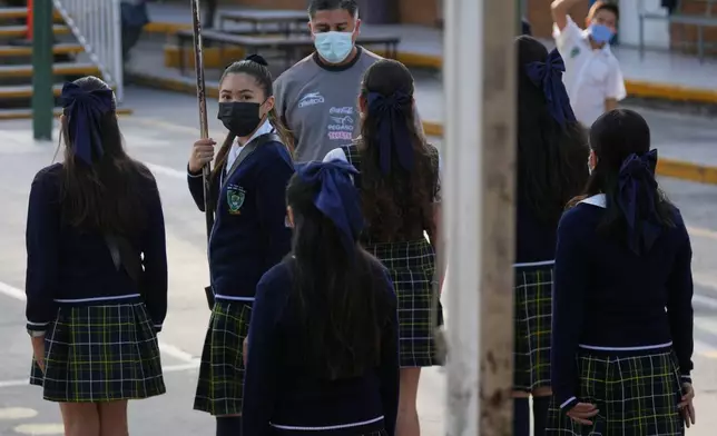 Public school students and teachers wear mandatory face masks amid a measles outbreak, during a ceremony at their school in Guadalajara, Mexico, Thursday, Feb. 5, 2026. (AP Photo/Fernando Llano)