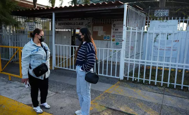 Parents of students wear face masks, made mandatory amid a measles outbreak, as they wait outside of a public school in Guadalajara, Mexico, Thursday, Feb. 5, 2026. (AP Photo/Fernando Llano
