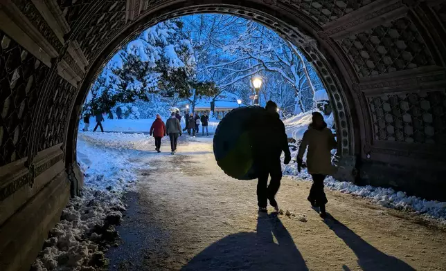 A man carries an inflatable inner-tube for snow sledding in Prospect Park in the borough of Brooklyn, New York, on Monday, Feb. 23, 2026. (AP Photo/Drew Callister)