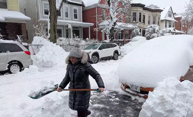 Christa Prince shovels snow during a blizzard in the borough of Brooklyn, New York, on Monday, Feb. 23, 2026. (AP Photo/Drew Callister)