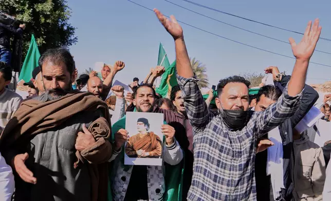 Libyans march to attend the funeral of Seif al-Islam, son of former Libyan Leader Moammar Gadhafi, as they hold a poster of his father in Bani Walid city, Libya, Friday, Feb. 6, 2026. (AP Photo/Yousef Murad)