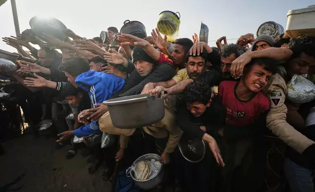 Displaced Palestinian struggle to receive donated food for iftar, the fast-breaking meal, on the first day of the Muslim holy month of Ramadan at a community kitchen in Khan Younis, Gaza Strip, Wednesday, Feb. 18, 2026. (AP Photo/Jehad Alshrafi)