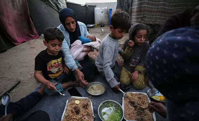 Displaced members of the Al-Zamli family break their fast on the first day of Ramadan inside their tent in Khan Younis, Gaza Strip, Wednesday, Feb. 18, 2026. (AP Photo/Jehad Alshrafi)