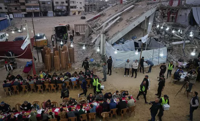 Palestinians sit at a long table amid the rubble of destroyed buildings as they gather for iftar, the fast-breaking meal, on the first day of the Muslim holy month of Ramadan in Khan Younis, Gaza Strip, Wednesday, Feb. 18, 2026. (AP Photo/Abdel Kareem Hana)
