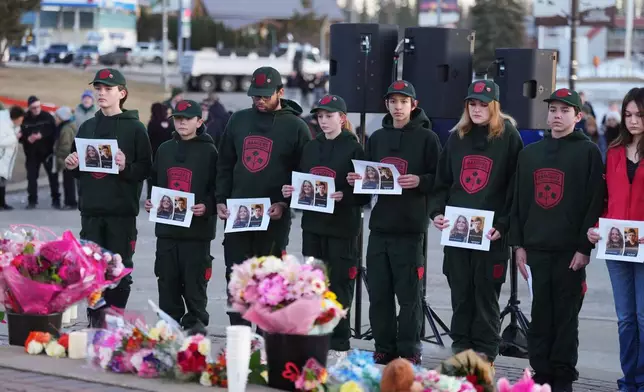 People hold photos of victims to a vigil for the victims of a mass shooting, in Tumbler Ridge, B.C., Friday, Feb. 13, 2026. (Christinne Muschi/The Canadian Press via AP)