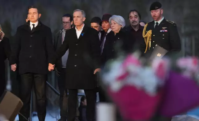 From left to right, Leader of the Official Opposition of Canada Pierre Poilievre, Prime Minister Mark Carney and Governor General of Canada, Mary Simon join hands while attending a vigil for the victims of a mass shooting, in Tumbler Ridge, B.C., Friday, Feb. 13, 2026. (Christinne Muschi/The Canadian Press via AP)