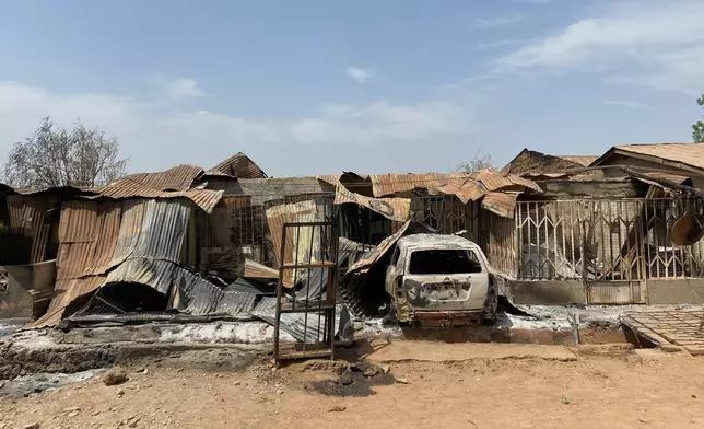 Charred homes and a vehicle stand in ruins days after an attack in the village of Woro, Nigeria, Thursday, Feb. 5, 2026. (AP Photo/Musa Salim)