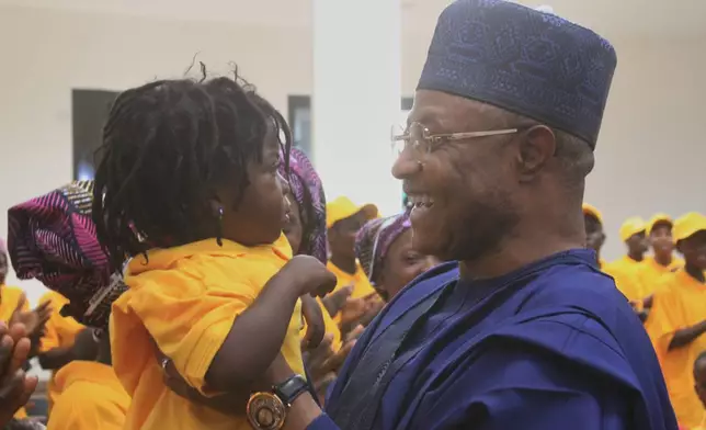 Kaduna State Governor, Uba Sani, right, holds a child, freed with other worshipers, abducted by gunmen in Kurmin Wali, upon their arrival at the state government house in Kaduna, Nigeria, Thursday, Feb. 5, 2026. (AP Photo/Abel Omotosho)