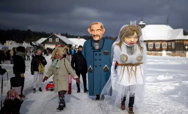 Performers dressed as newlyweds take part in Shrovetide celebrations in the village of Rumsiskes, some 89 kilometers (56 miles) north of Vilnius, Lithuania, Saturday, Feb. 14, 2026. (AP Photo/Mindaugas Kulbis)