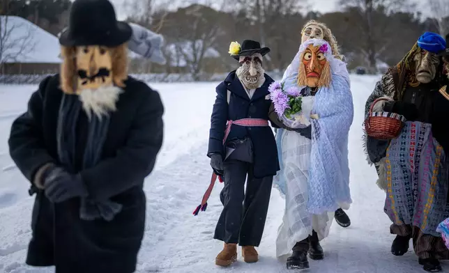 Performers dressed as newlyweds take part in Shrovetide celebrations in the village of Rumsiskes, some 89 kilometers (56 miles) north of Vilnius, Lithuania, Saturday, Feb. 14, 2026. (AP Photo/Mindaugas Kulbis)